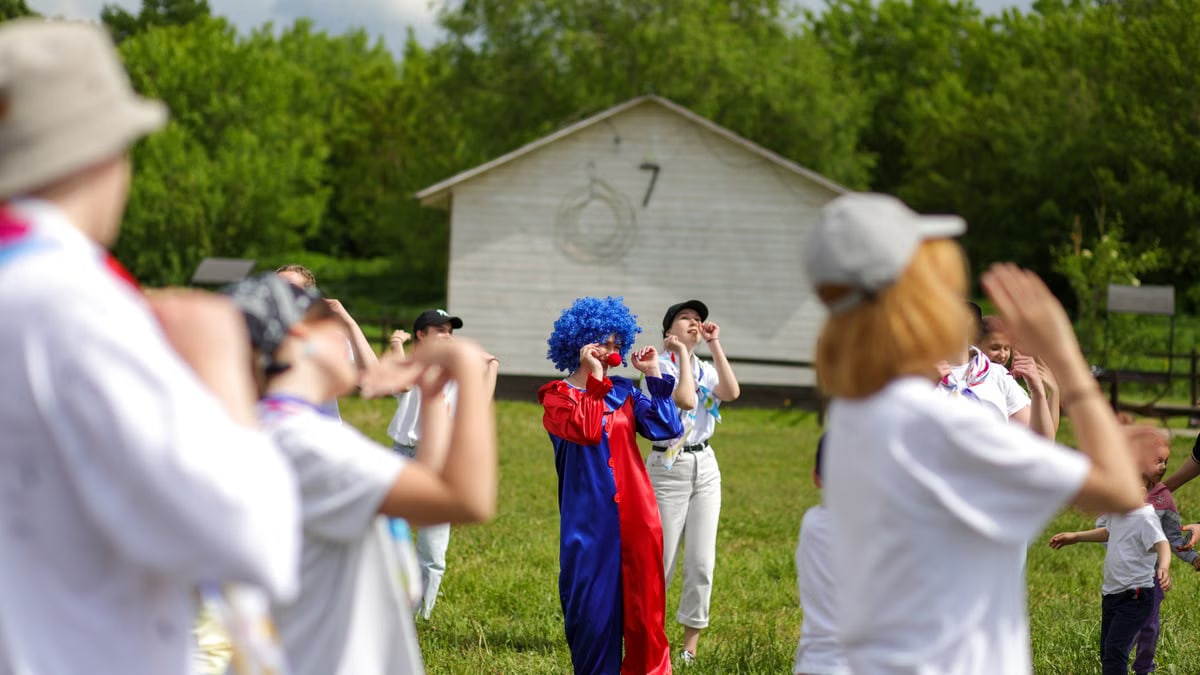 Group enjoying a clown performance in a sunny park setting. Perfect for summer festival themes.